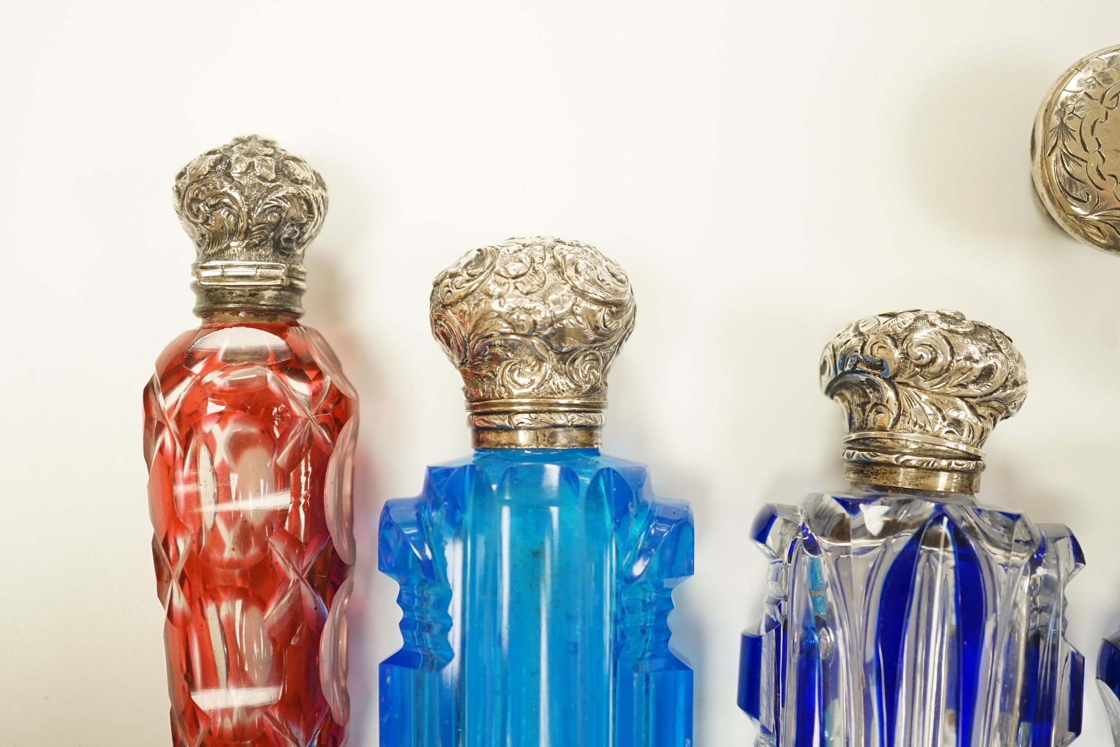 A late Victorian silver mounted cut glass scent bottle, Charles Boyton II, London, 1896, 82mm and six other late 19th/early 20th century, silver or white metal mounted coloured cut glass scent bottles (some a.f.) and two